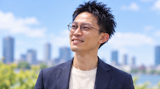 青空の下で、笑顔で前を向く男性